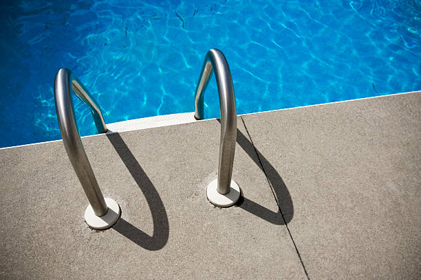 looking down at a pool ladder on a concrete deck.